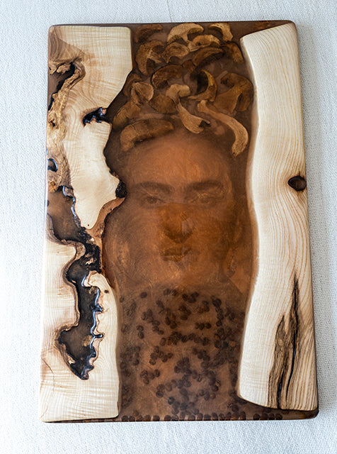 Image of Frida Kahlo in a piece of art that uses orange resin and wood
