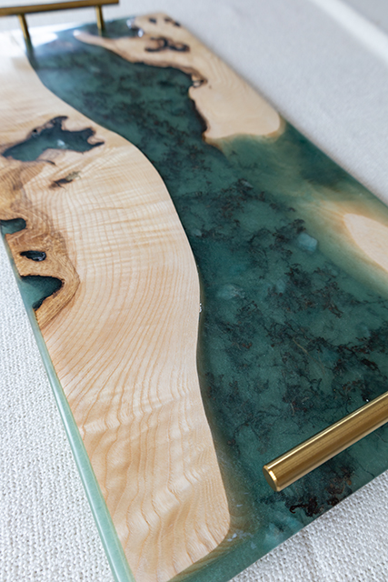 Tabla de servir artesanal detallada con combinación de madera natural y resina verde, con asas de latón