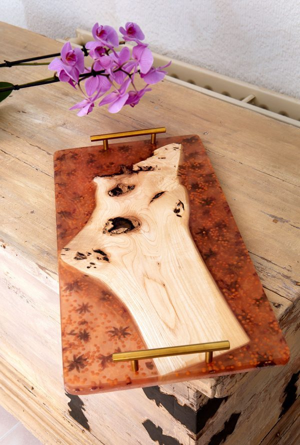 Mesa de servir de madera con acabado de resina translúcida ámbar y flores secas, sobre una base de madera rústica con asas de latón