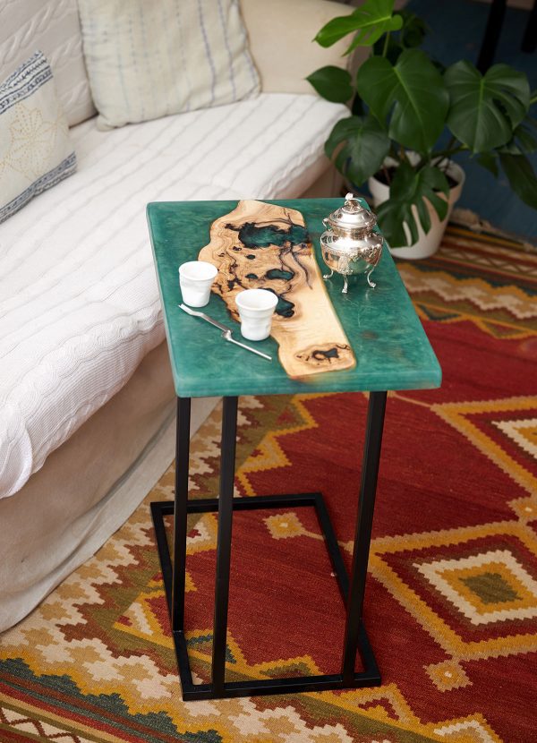 Elegante mesa auxiliar de madera y resina turquesa decorada con una tetera de plata y tazas de café, en un interior acogedor