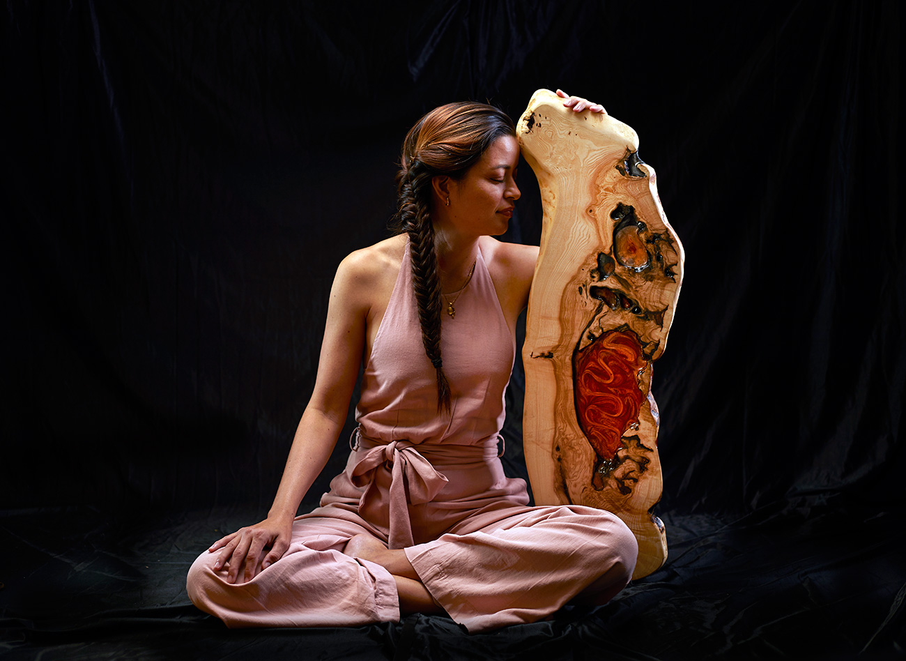 Mujer contemplativa junto a una impresionante obra de arte en madera y resina, reflejando la conexión entre el arte y el espectador