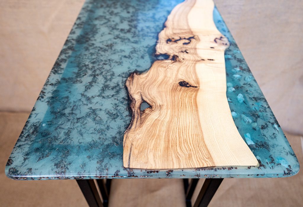Mesa de comedor contemporánea de madera natural y resina azul con patrón de efecto mármol.