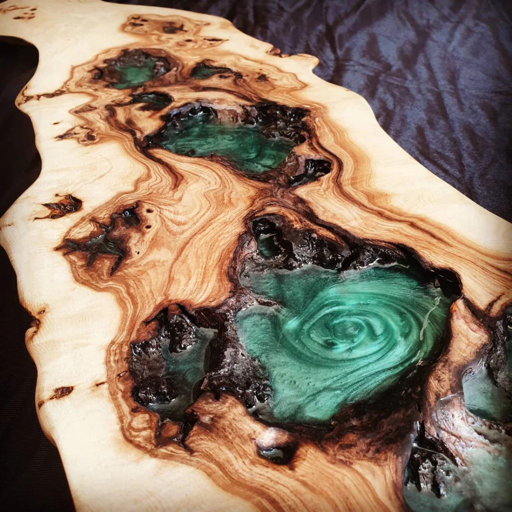Pieza artística de madera con incrustaciones de resina turquesa, mostrando una mezcla de texturas naturales y colores vibrantes