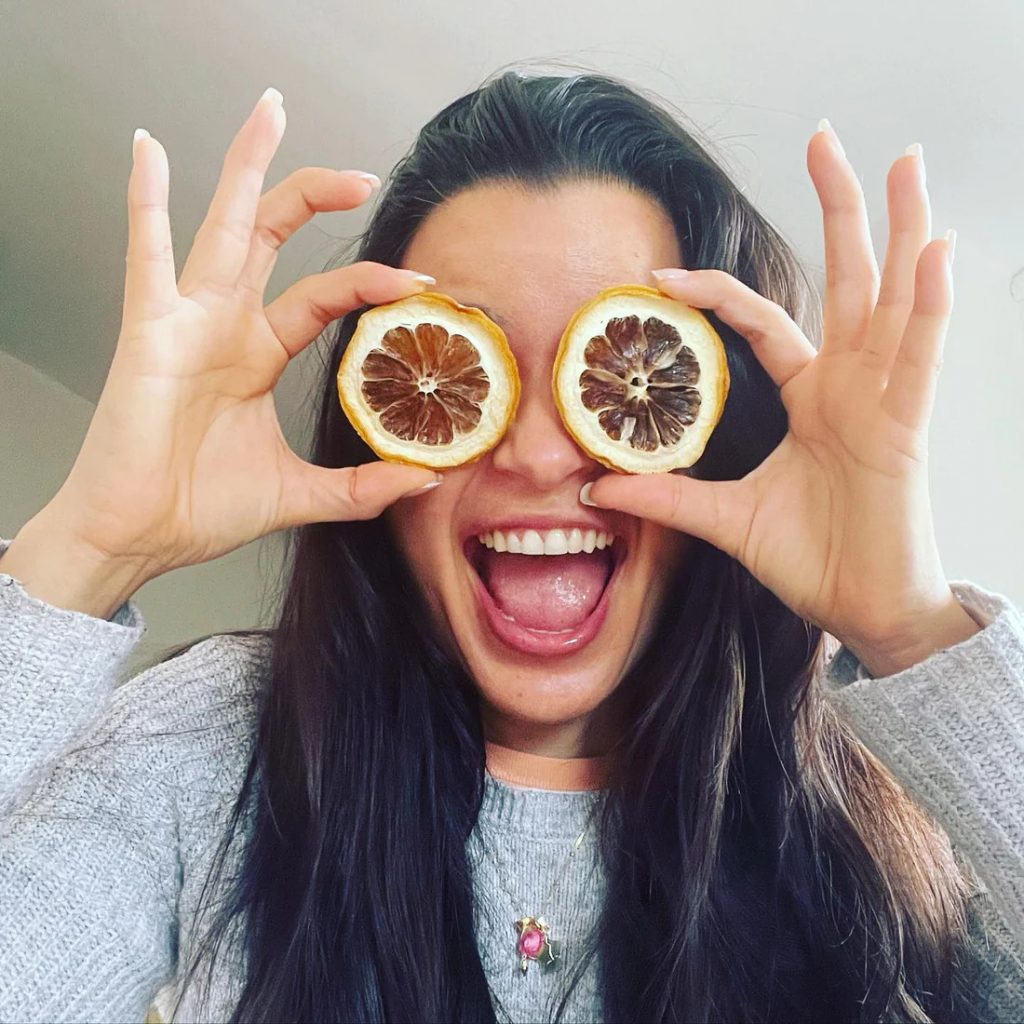Mujer alegre utilizando rodajas de limón como gafas, simbolizando diversión y bienestar