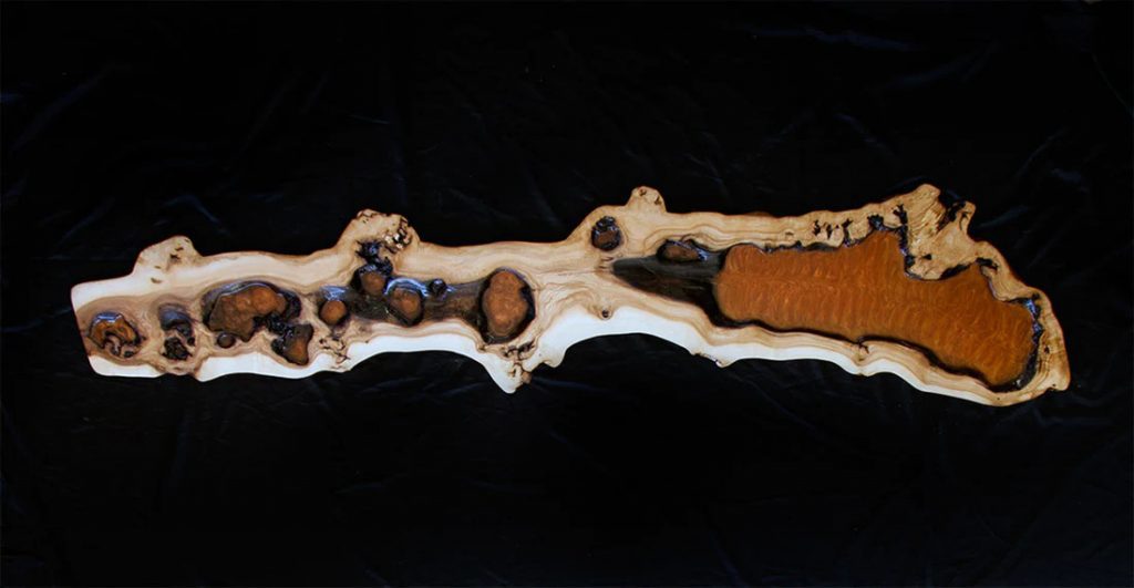Pieza alargada y sinuosa de madera natural con resina sobre fondo negro