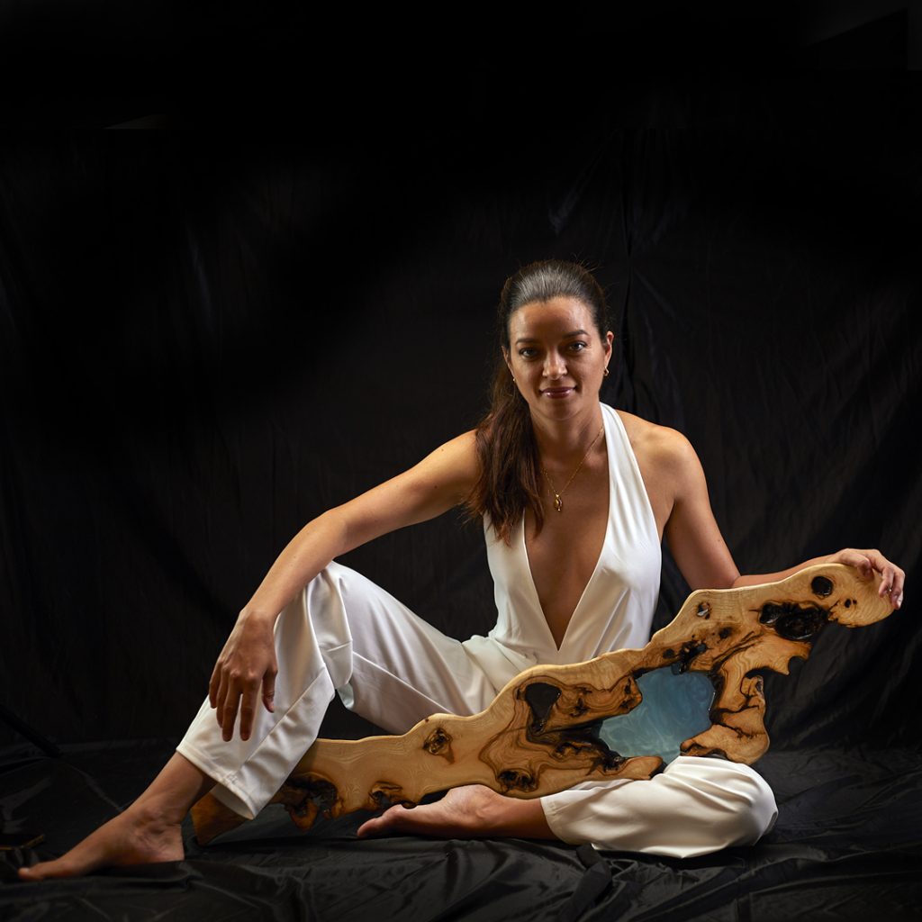 Mujer en atuendo elegante interactuando con una repisa de madera y resina, mostrando su versatilidad y belleza.