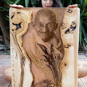 Persona sosteniendo una tabla de madera artística con una imagen grabada y elementos de diseño natural