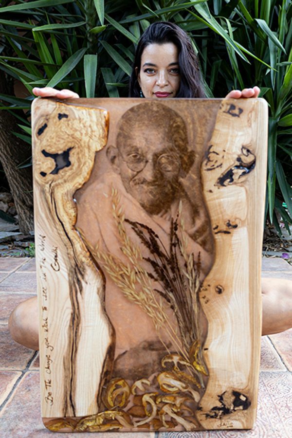 Persona sosteniendo una tabla de madera artística con una imagen grabada y elementos de diseño natural