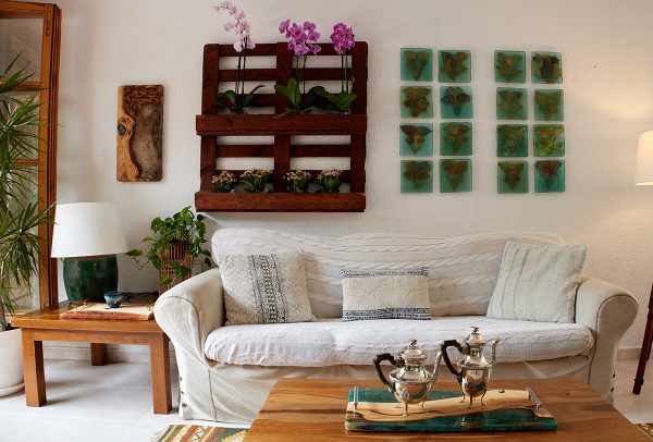 Rincón acogedor de sala de estar con un sofá blanco, mesa de café de madera y una pared adornada con arte botánico y un plantador rústico de madera con orquídeas