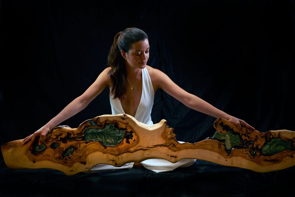 Mujer sosteniendo una repisa de madera y resina, destacando su diseño orgánico y artístico