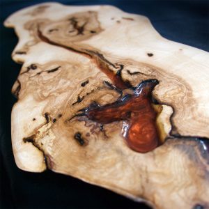 Repisa de madera que ondula con una vena de resina marrón oscuro, imitando un camino forestal