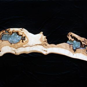 Repisa de madera alargada y curvada con múltiples depósitos de resina azul y negra