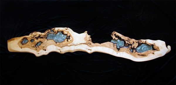 Repisa de madera alargada y curvada con múltiples depósitos de resina azul y negra