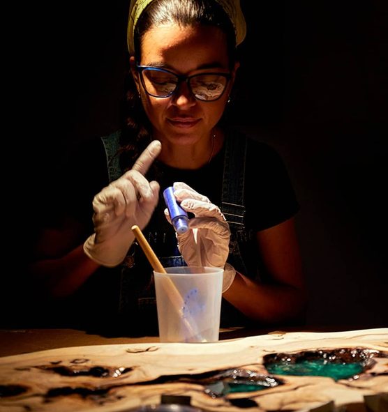 Artesana trabajando con resina en un taller iluminado con foco.