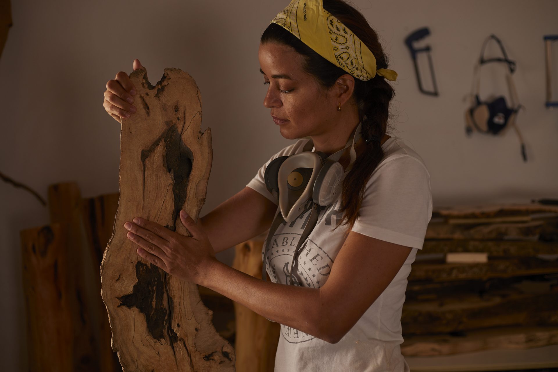 Artesana examinando una pieza de madera en su taller.