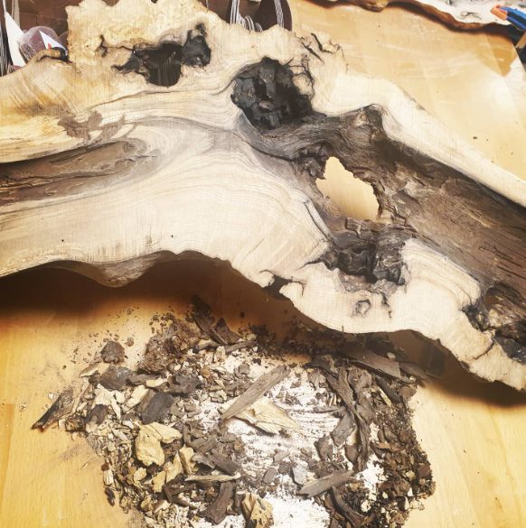 Trozo de madera con cavidades y restos de carpintería en una mesa.