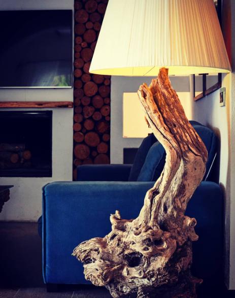Lámpara de pie única con base de madera retorcida en una sala con chimenea.