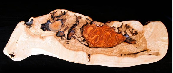 Pieza artística de madera con remolino de resina naranja y marrón sobre fondo negro
