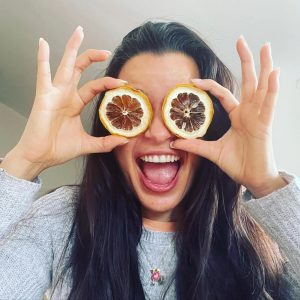 Momento espontáneo de felicidad capturado mientras una mujer se divierte con rodajas de limón, añadiendo un toque de humor a la vida cotidiana