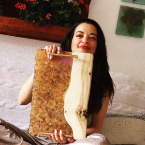 Una sonrisa que refleja la satisfacción de un trabajo bien hecho, mostrando una creativa tabla de madera y resina.